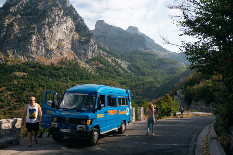 Blue minibus on a winding road in the Albanian Alps