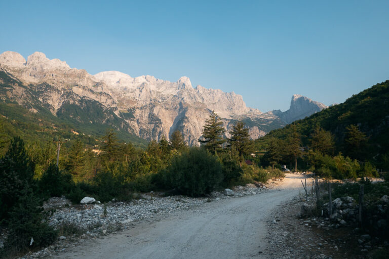 Dirt road leading to jagged grey peaks in the Albanian Alps