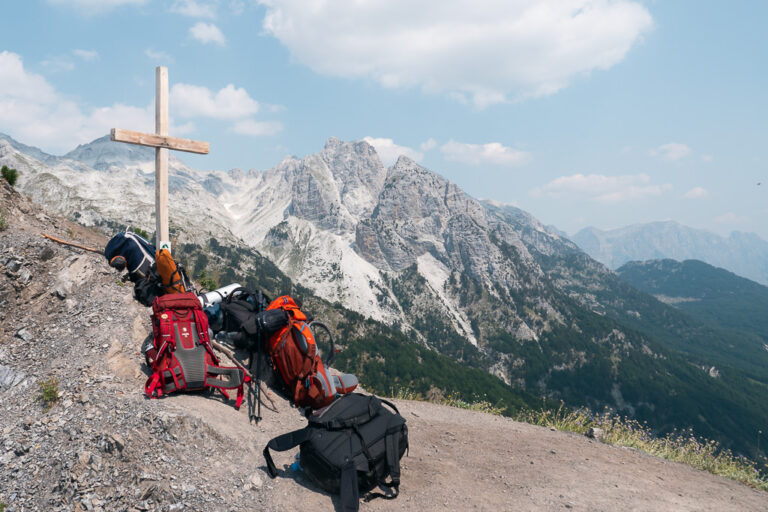 Wooden cross and hiking packs on a ridge in the Albanian Alps
