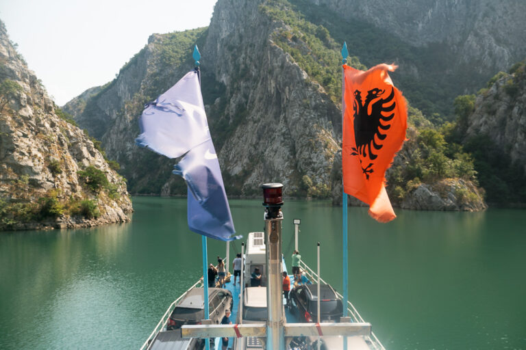 View from a ferry on Komani Lake, drifting towards towering green cliffs