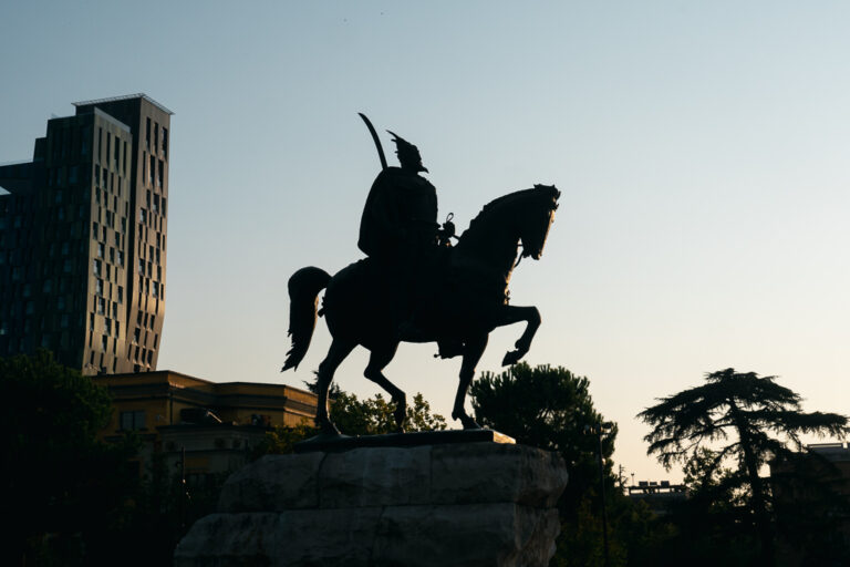 A dramatic silhouette of the Skanderbeg Monument in Tirana, Albania