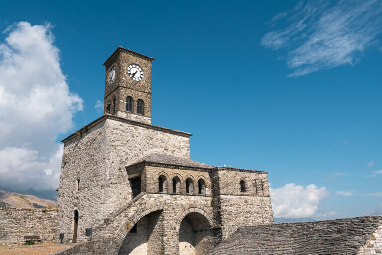 Gjirokaster Castle with a clock tower; blue sky and white clouds in the background