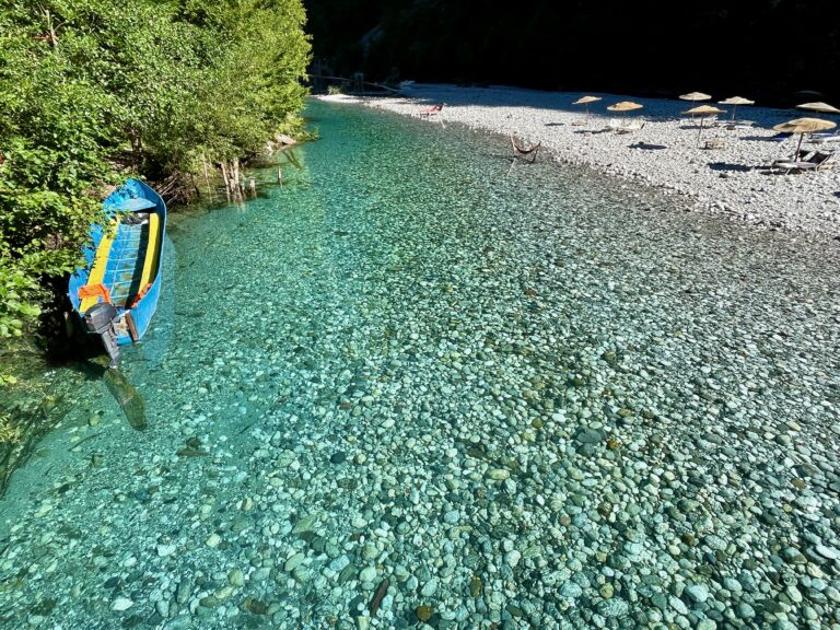 Shala River in Albania, showing a boat moored by the lush bank
