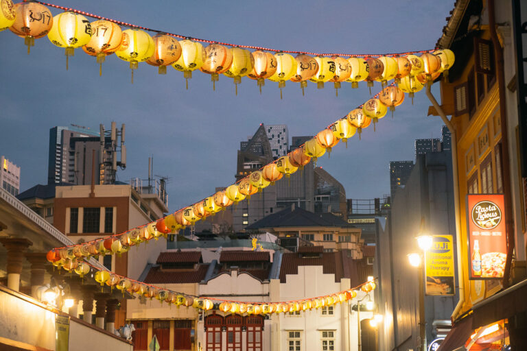 illuminated Chinese lanterns hang across a street in Singapore's Chinatown at dusk