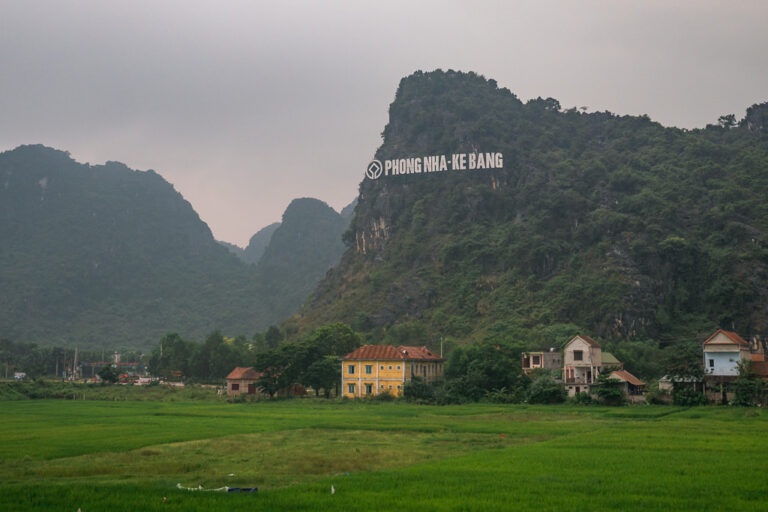Phong Nha-Ke Bang National Park green rice fields and a cluster of houses at the foot of a lush mountain