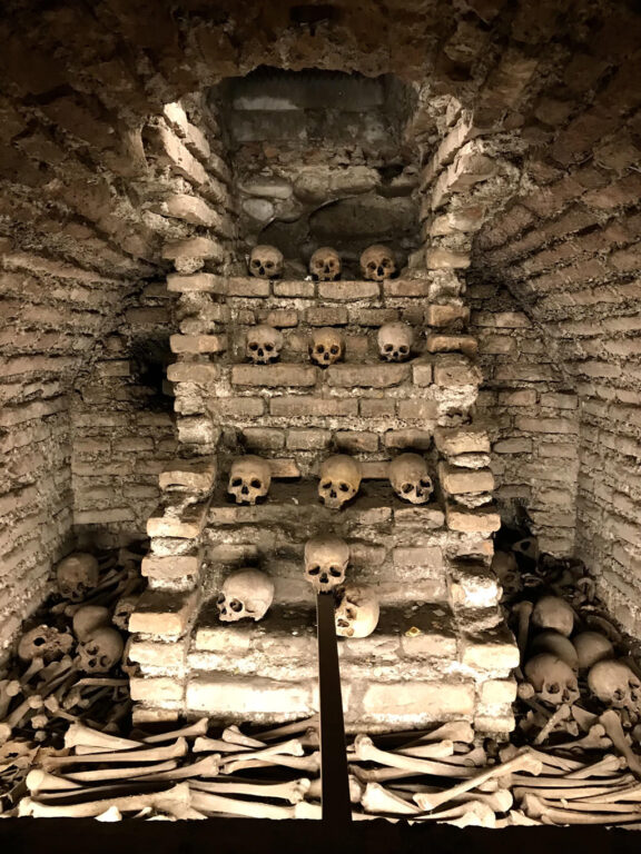 Rows of human skulls and bones on a brick wall inside the San Francisco Catacombs