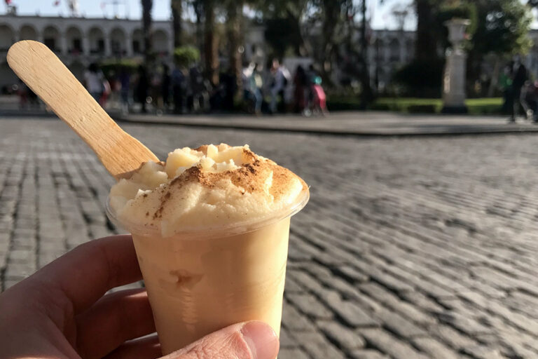 cup of queso helado, held in front of a blurred Plaza de Armas