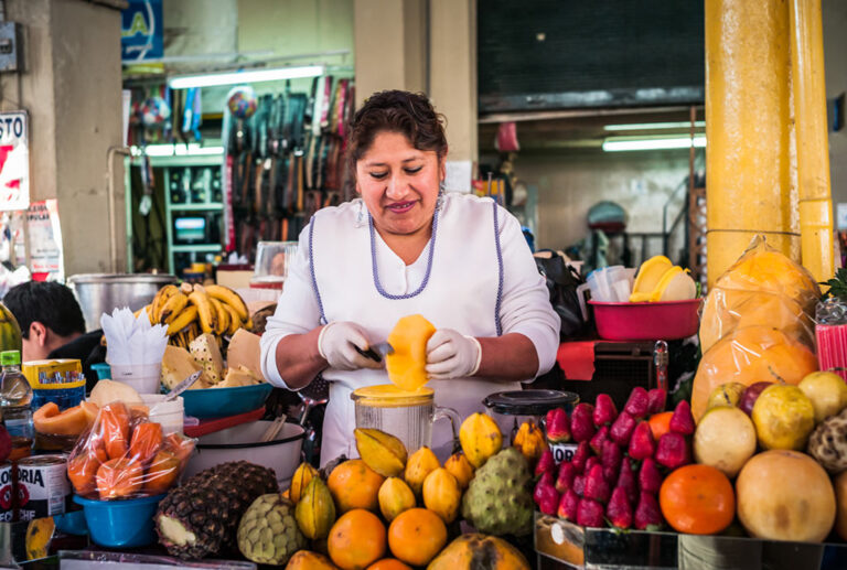 A woman peeling fresh fruit at a market stall in Arequipa's San Camilo Market