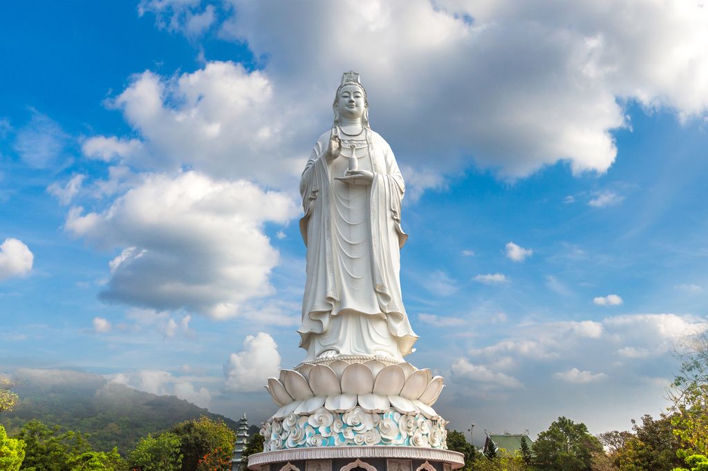 White statue of Lady Buddha with the sky in the background