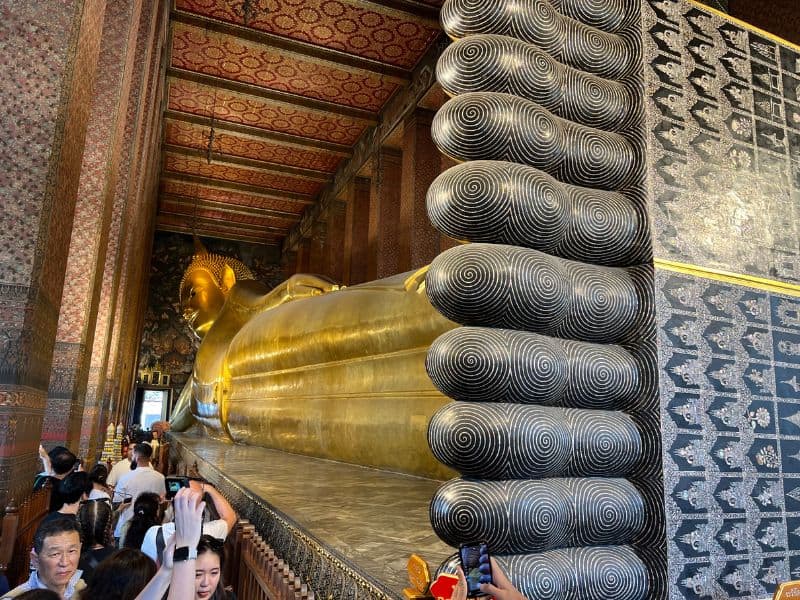 Tourists at the Reclining Buddha statue in Wat Pho, Bangkok, Thailand.