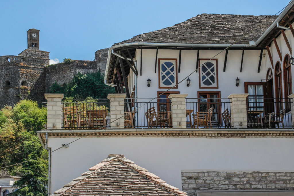 Whitewashed traditional Gjirokaster house with a stone roof and an outdoor patio overlooking Gjirokaster castle