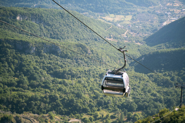 A cable car suspended over a deep, forested valley in Tirana, Albania