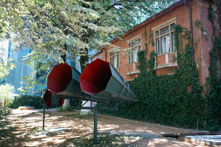 Exterior of the House of Leaves showing a red brick museum and three metal horn sculptures