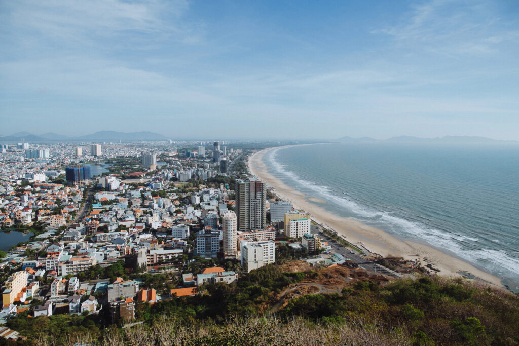 a landscape view of Vung Tau with dense city buildings curving along a long sandy beach
