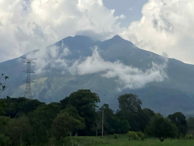 green-sloped mountain shrouded by clouds