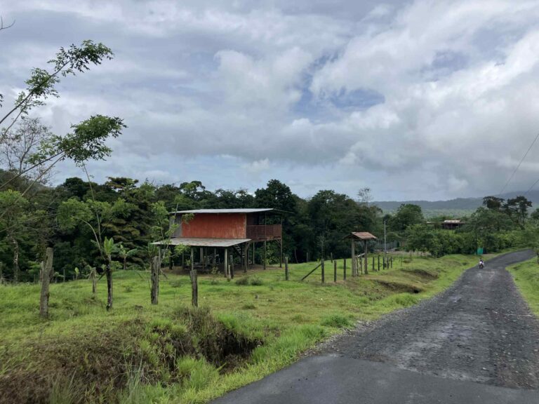 rural road through fields with a rustic wooden house the Guanacaste foothills