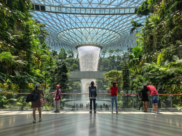 Rain Vortex cascading from the roof structure inside the Jewel at Singapore Changi Airport with people taking pics of it