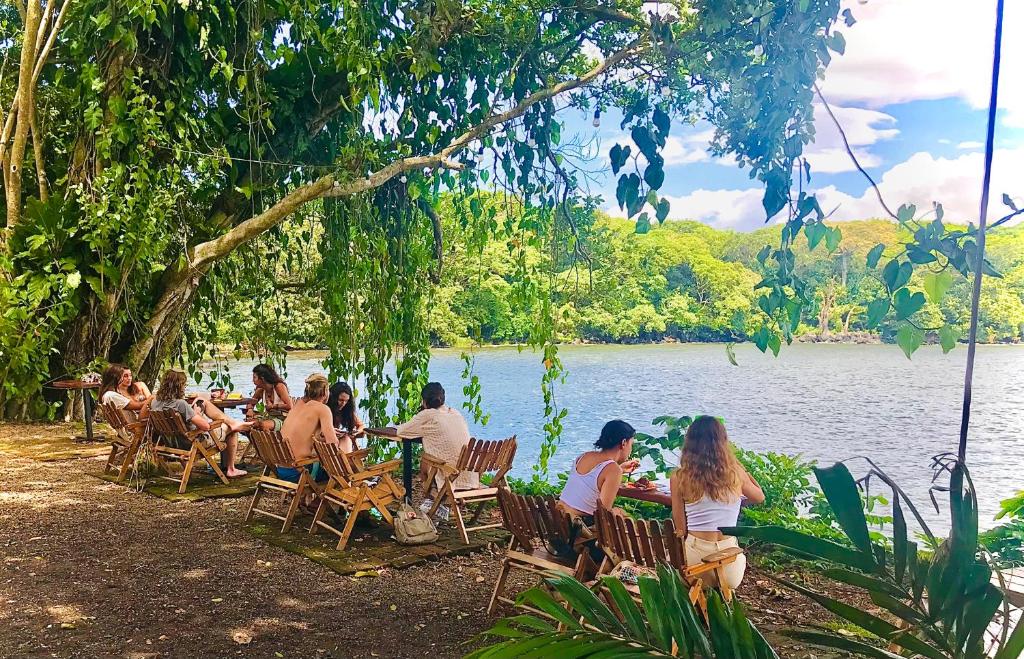 people relaxing at wooden tables on terrace surrounded by greenery and looking over Nicaragua lake at El Pital on Ometepe Island
