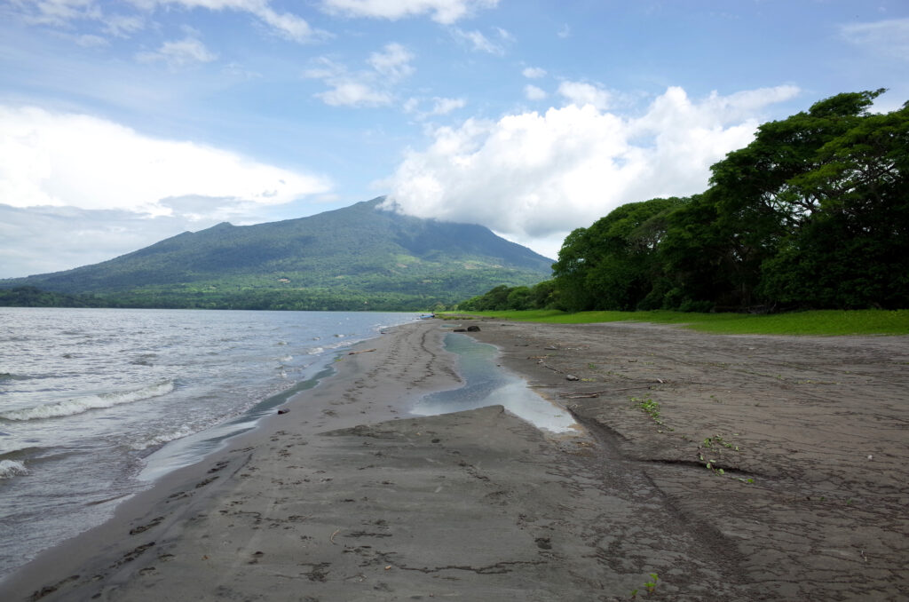 Volcan Maderas rising behind Ometepe’s black-sand shoreline — Playa Santa Cruz
