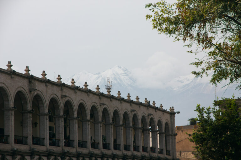 Stone arches of the Plaza de Armas in Arequipa, Peru, with snow-capped mountains in the background