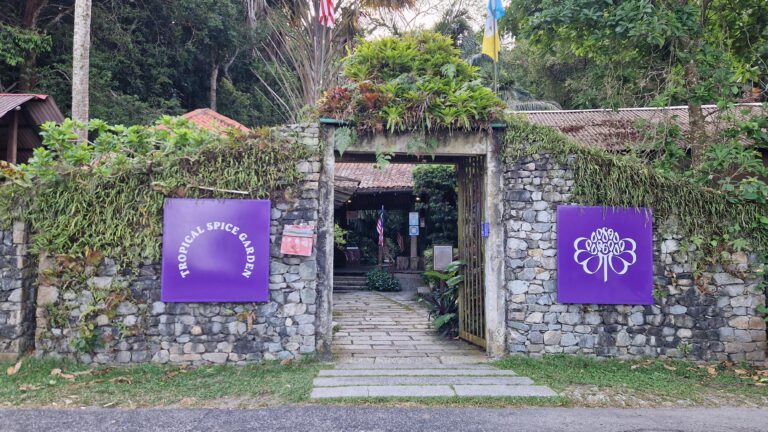 The entrance to the Tropical Spice Garden in Penang, featuring a stone wall with a central gateway