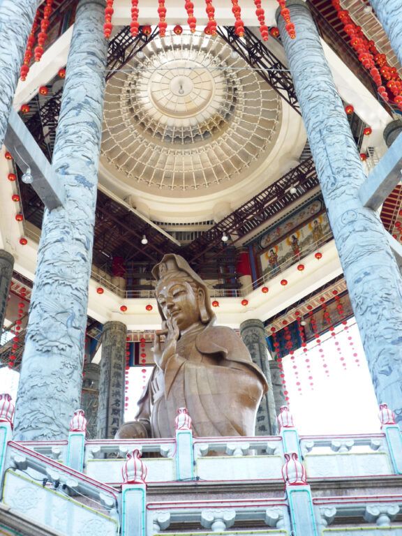 A giant bronze Guanyin statue under an pavilion dome with carved pillars at Kek Lok Si Temple