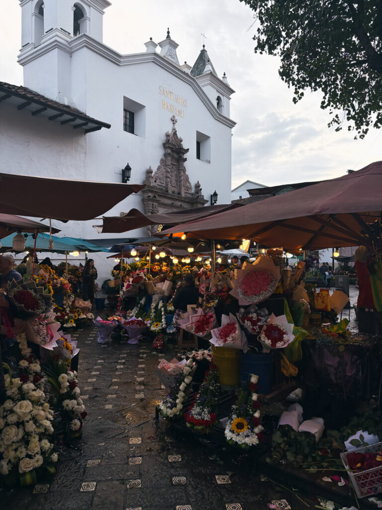 flower stalls sheltered by umbrellas fill the Plaza de las Flores right in front of the Santuario Mariano church in Cuenca