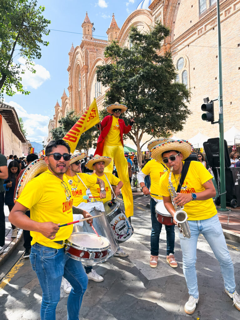 street band in yellow shirts and sombreros and a a stilt walker perform at a football match in Cuenca