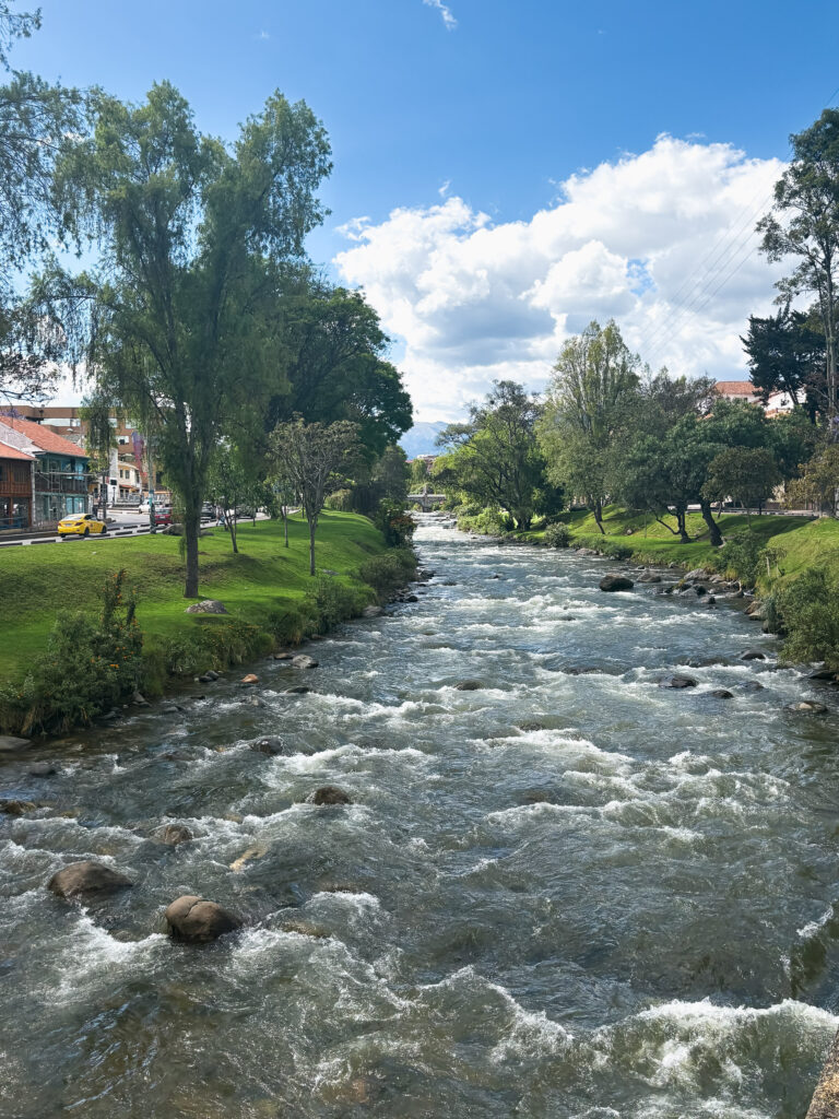 Río Tomebamba flows past the grassy banks lined by buildings
